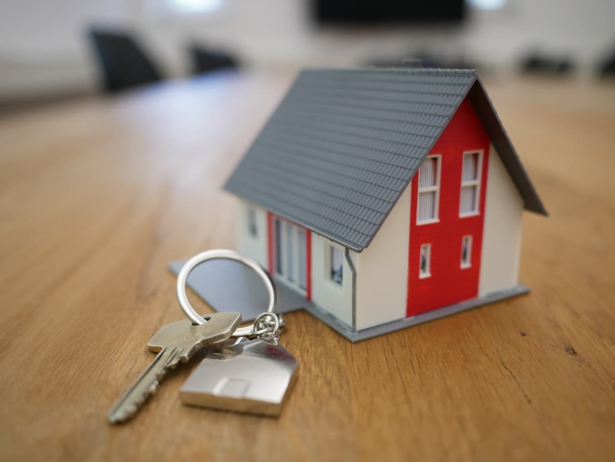 Small wooden house model next to a set of keys on a desk, representing homeownership and mortgage planning