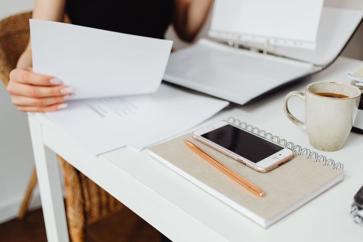 Clean white desk with planner notebook, smartphone, and coffee cup arranged neatly