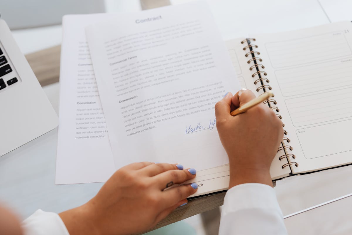 professional signing documents at a closing table with mortgage paperwork spread out