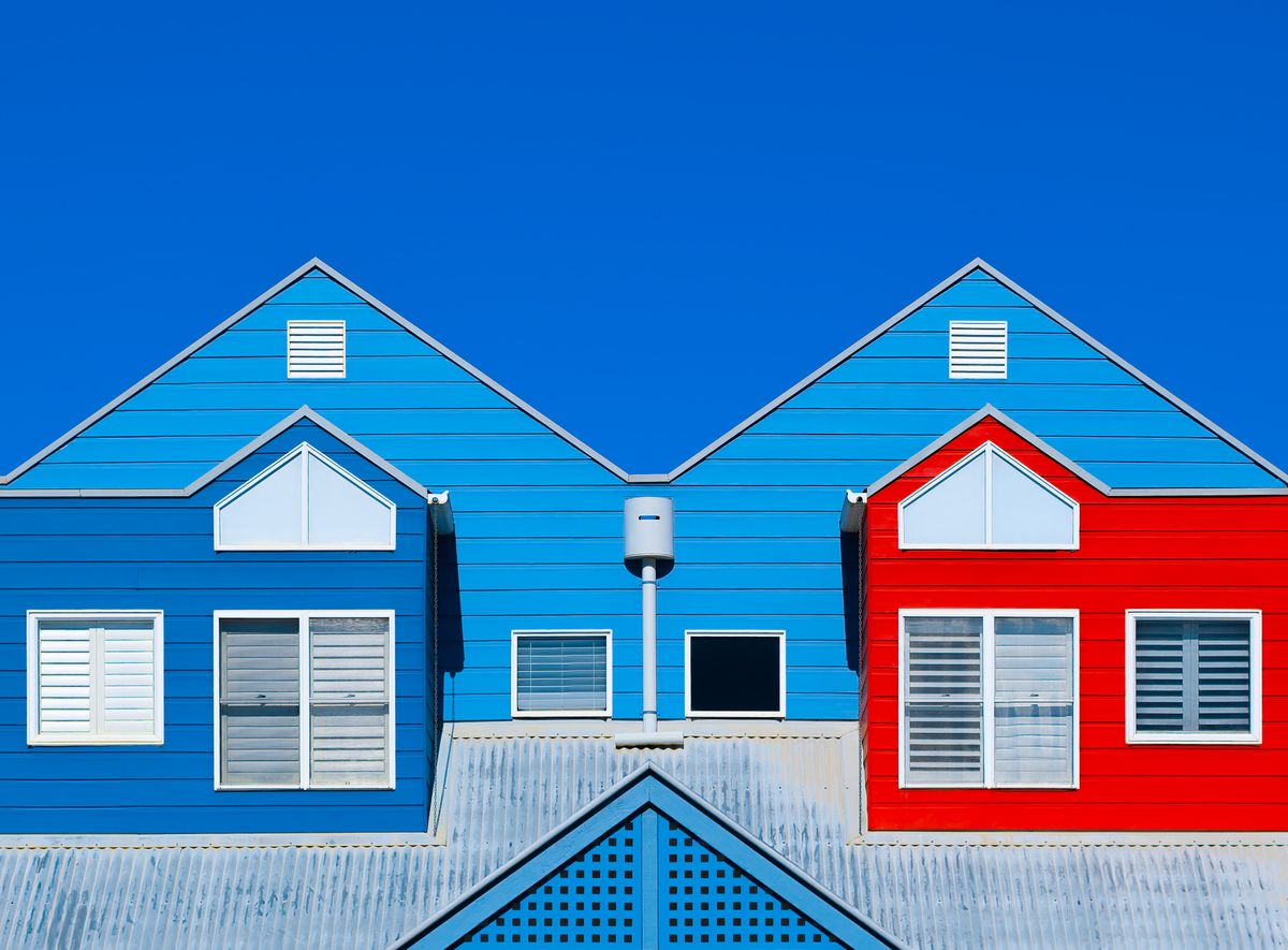 Colorful blue and red gables on a residential building against a clear blue sky
