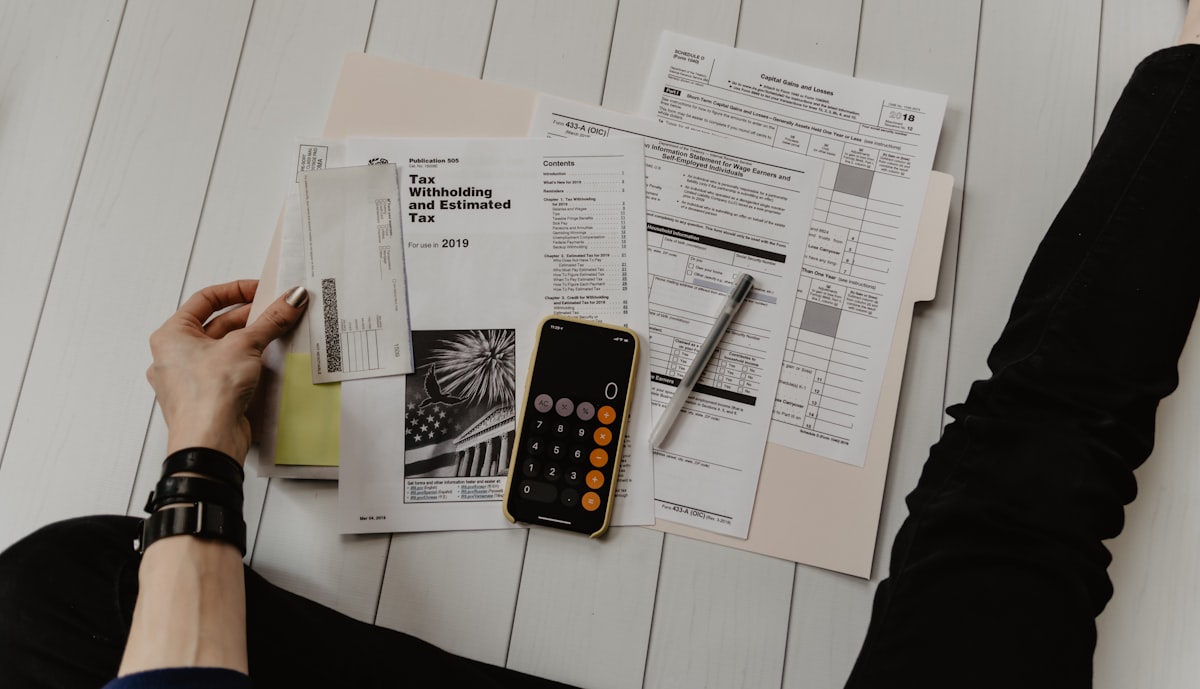 Notepad with financial calculations and a calculator on a wooden desk, representing home-buying budget planning