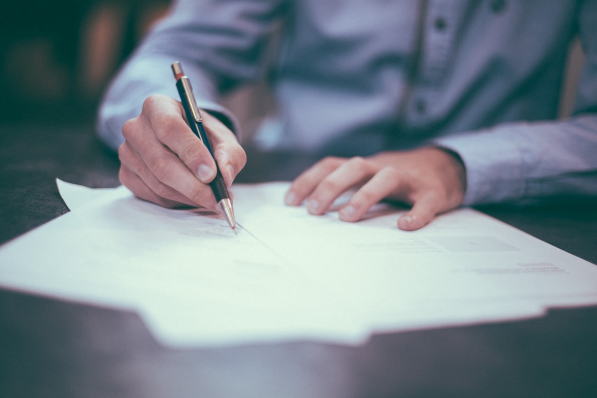 Person signing mortgage documents at a desk, finalizing a home loan agreement