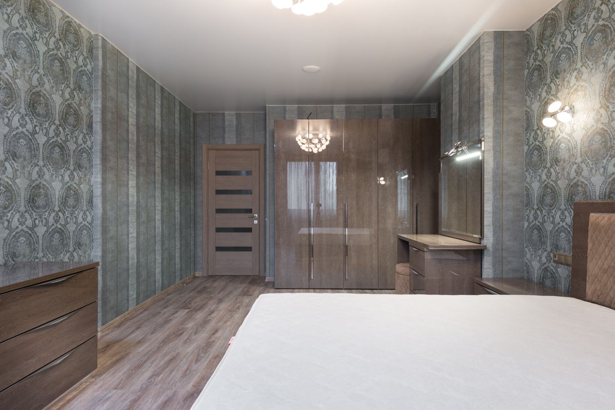 furnished bedroom with a white bedspread, wood wardrobe, and dressing table