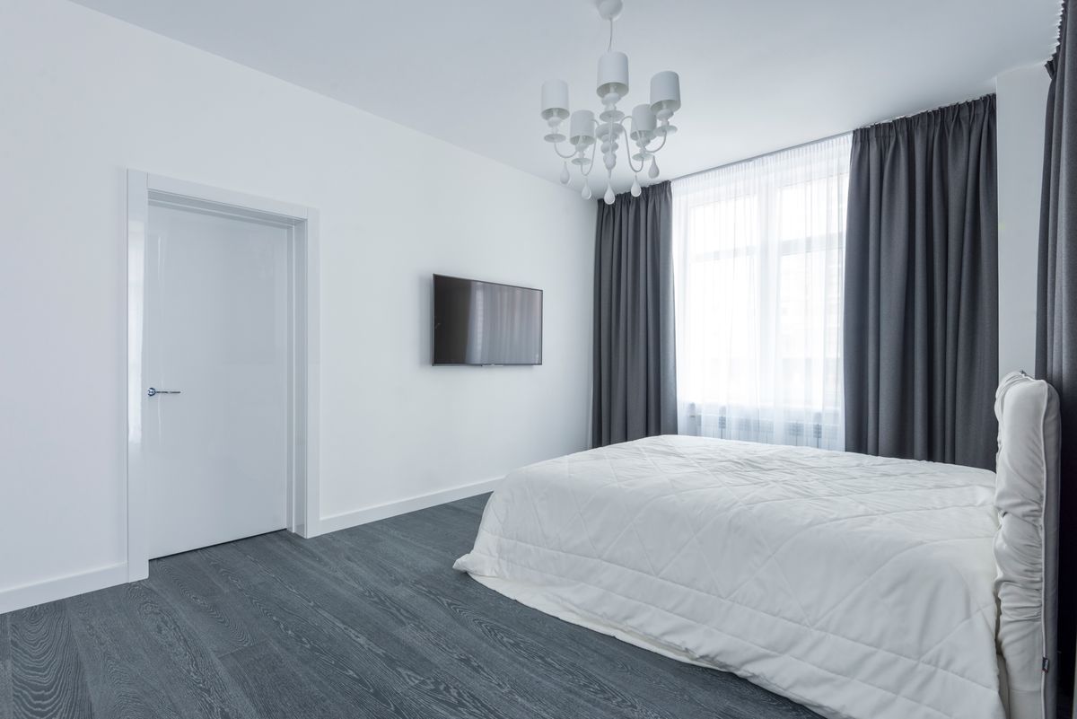 Bright bedroom with white bedding, gray curtains, and a large window