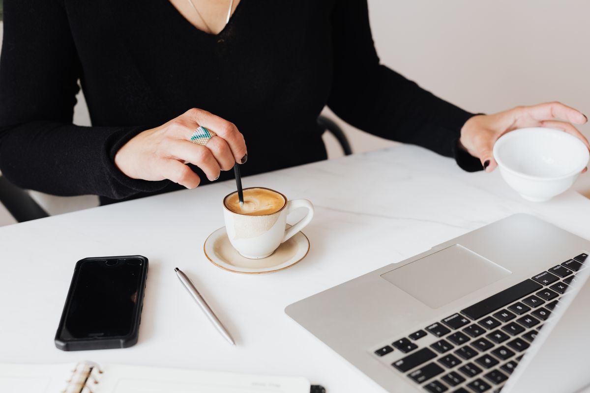 Professional working at a clean desk with coffee, phone, and laptop in a minimalist setup